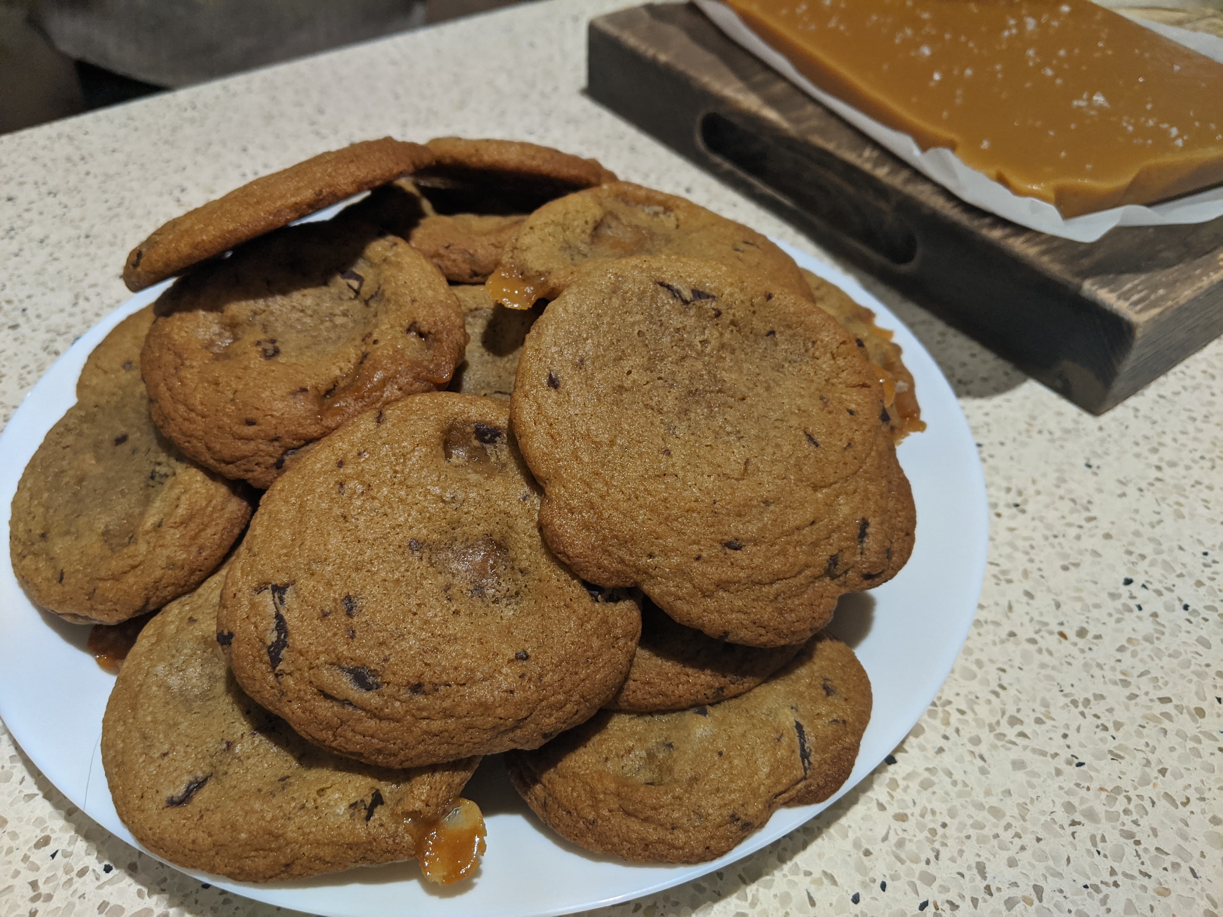A plate of cookies with chocolate chips and chunks of oozing caramel