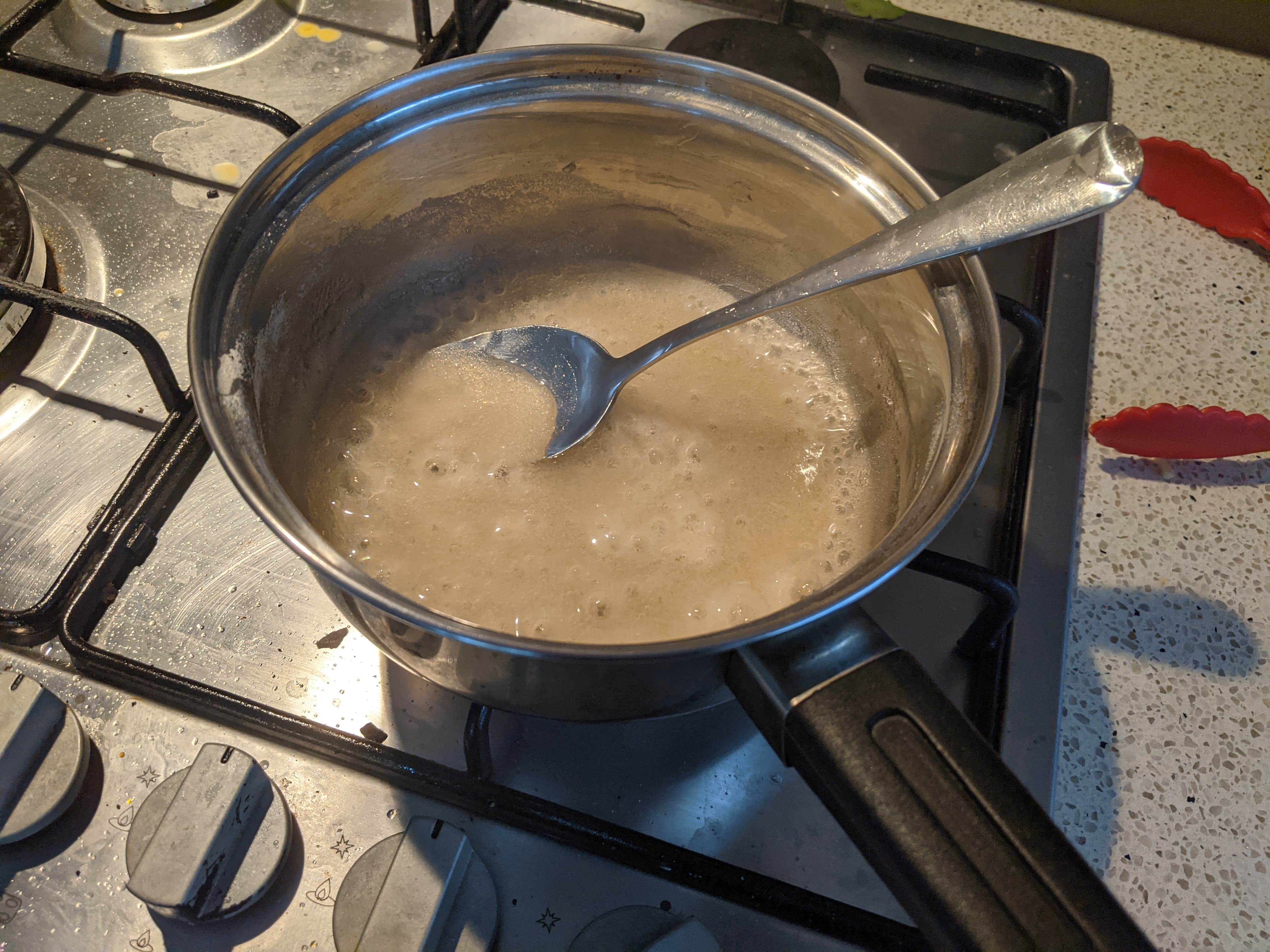 A yellow agar agar mixture boiling in a small saucepan on the stove