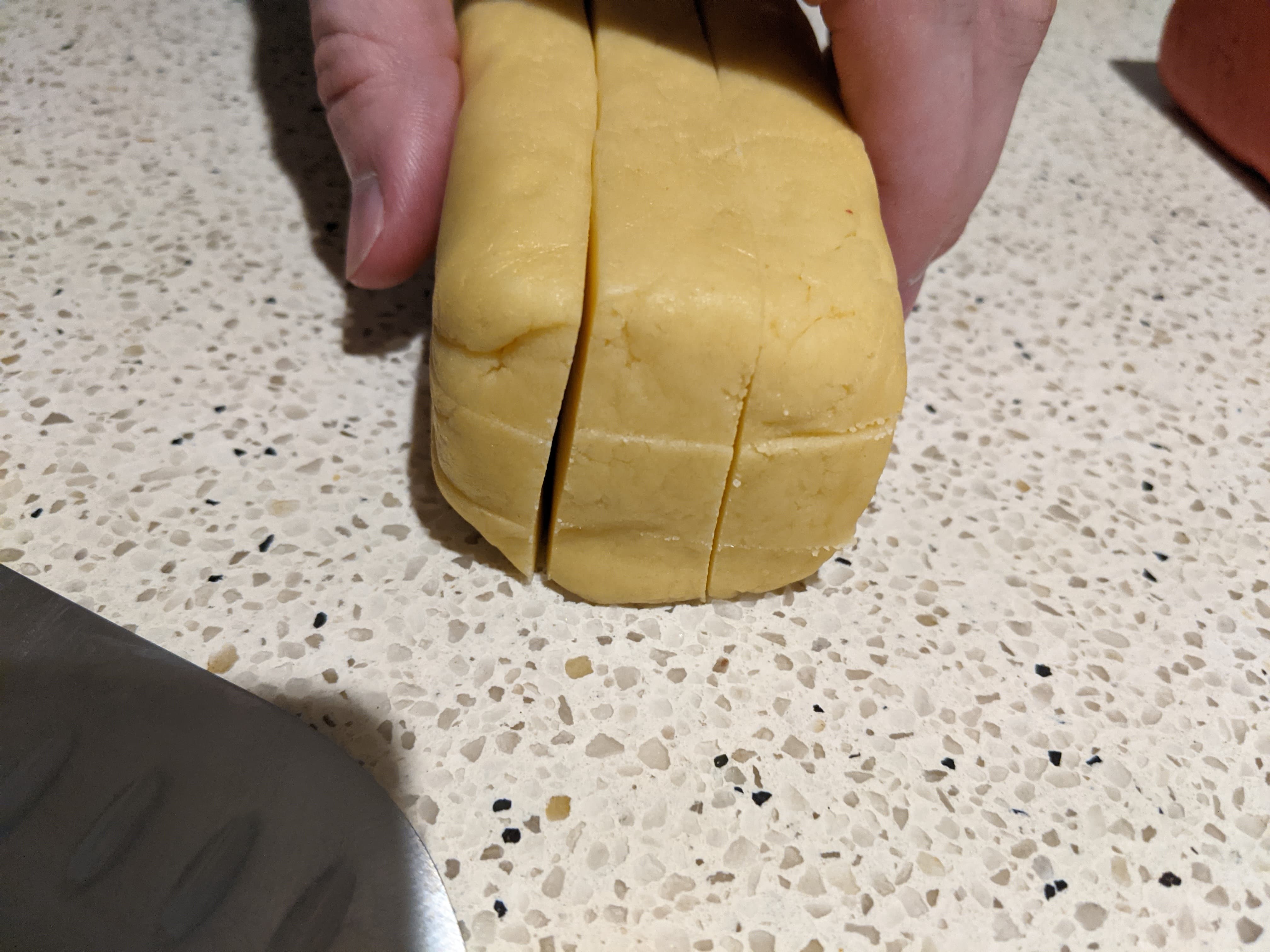 A log of cookie dough sliced into 9 equal sections lengthways, pictured from one end