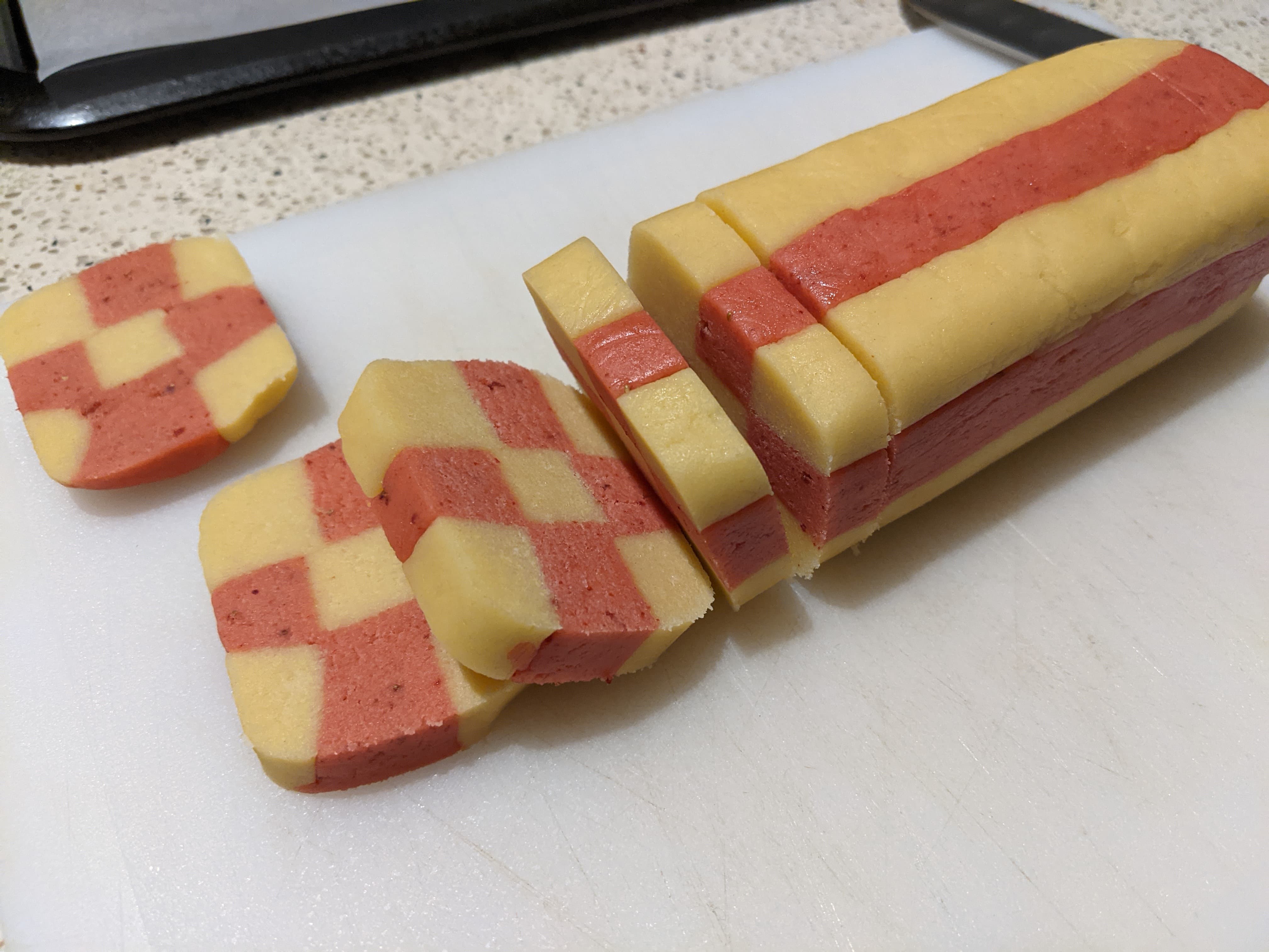 A log of checkerboard cookie dough that has been sliced from one end into 1cm wide pieces