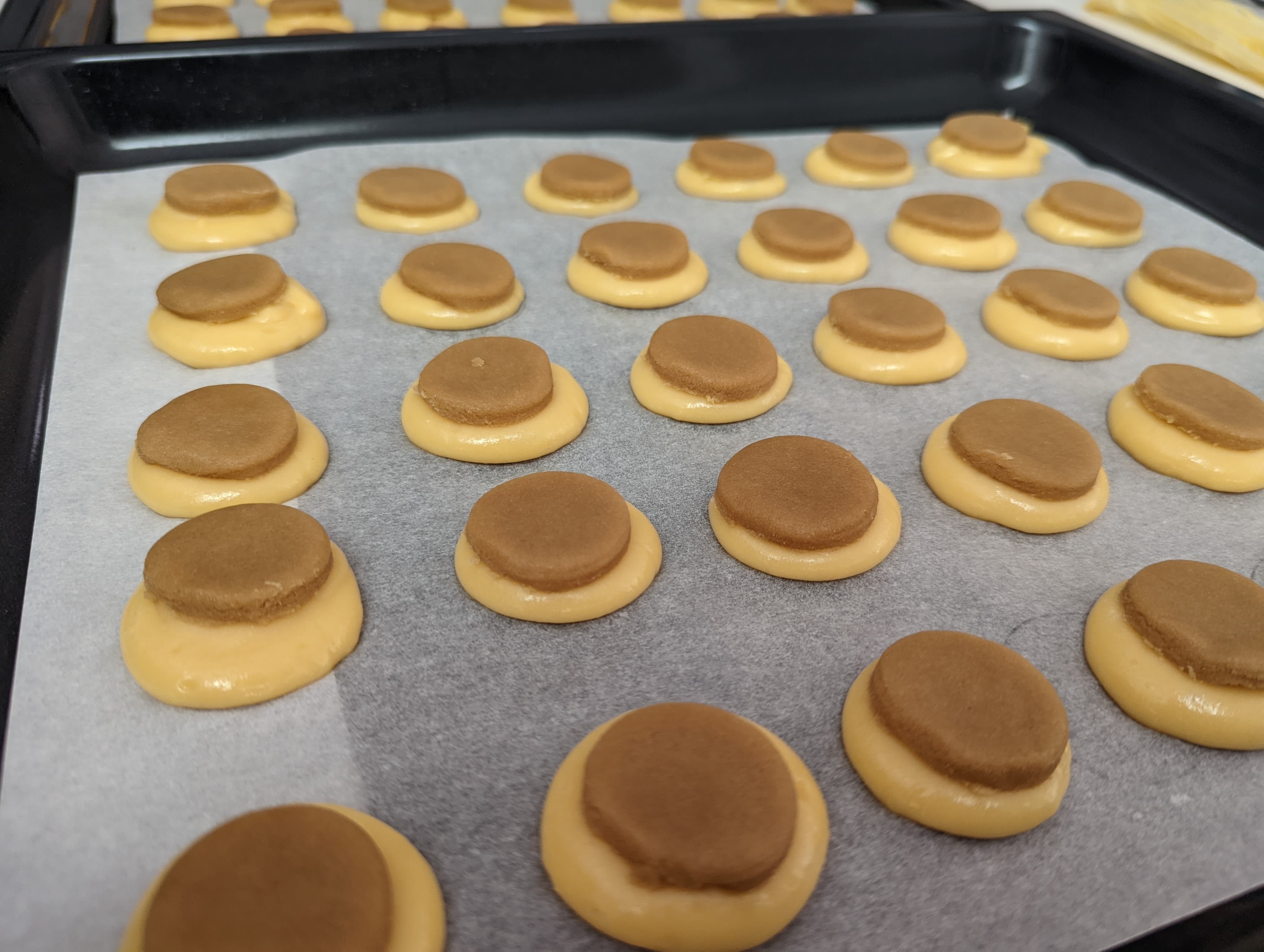 A tray of choux pastry piped into neat circles, each one with a round of craquelin placed on top