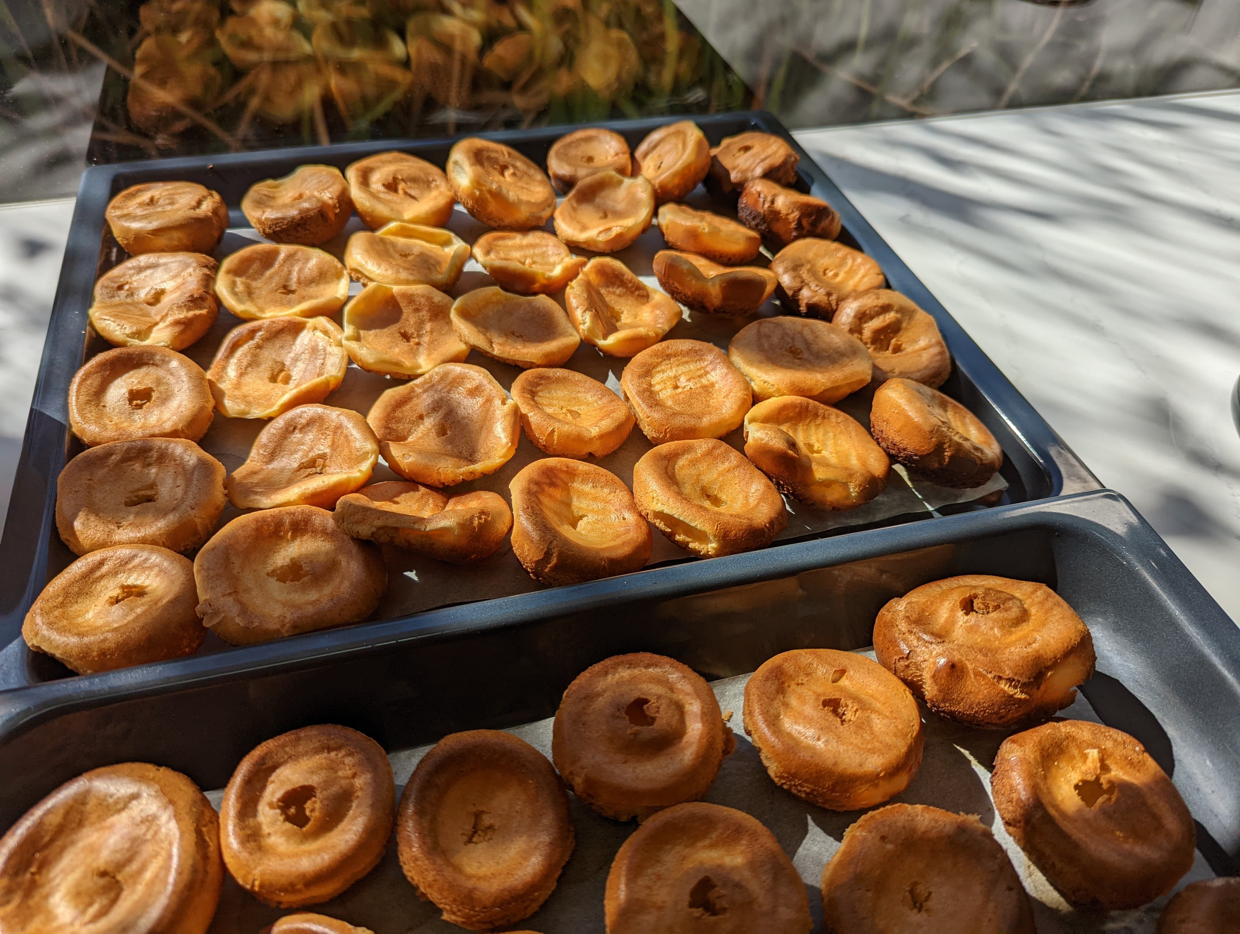 Trays of baked choux pastry all turned upside down, and with holes poked in the bottom