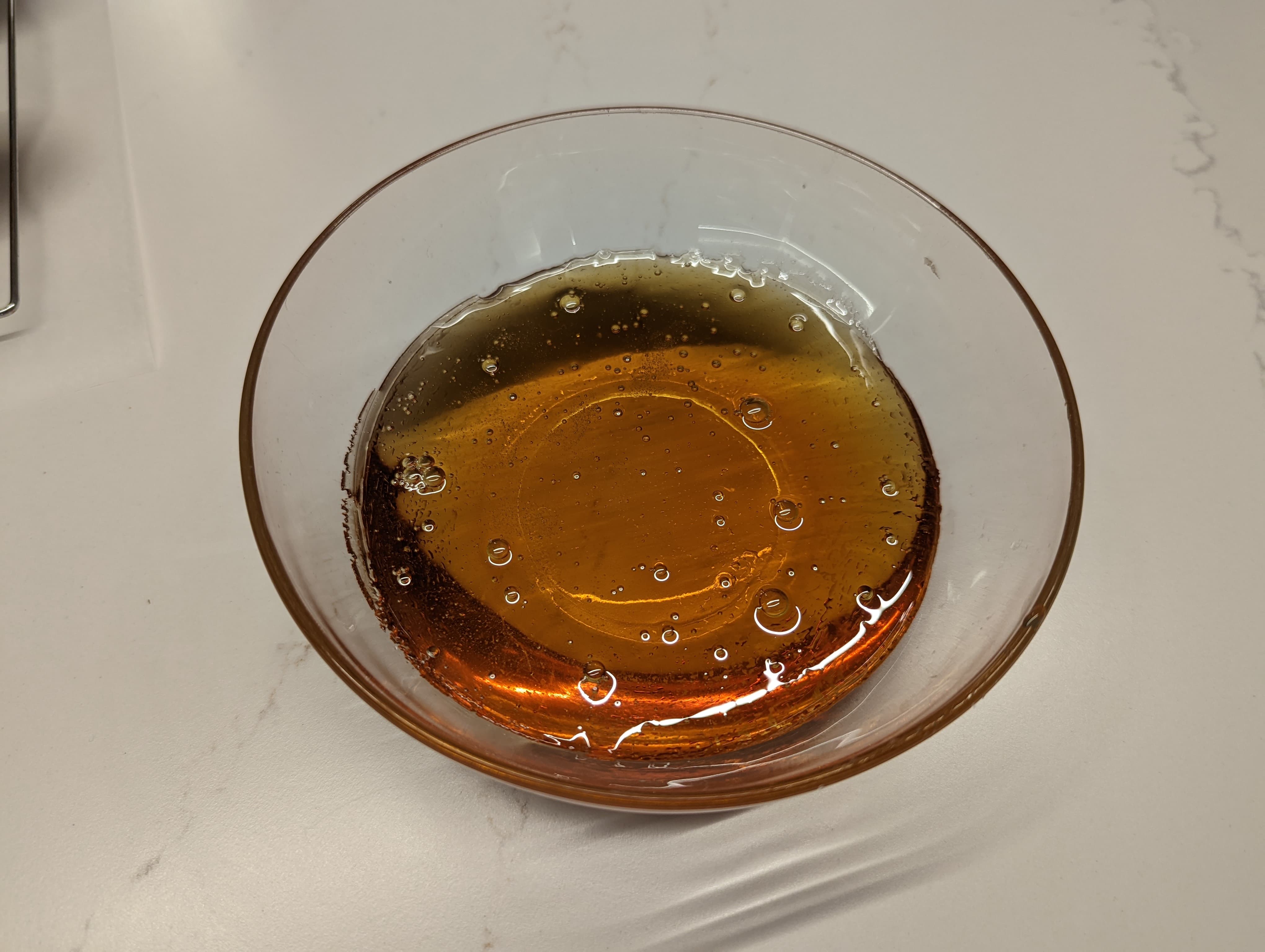 A small glass bowl filled with a golden transparent molten caramelized sugar
