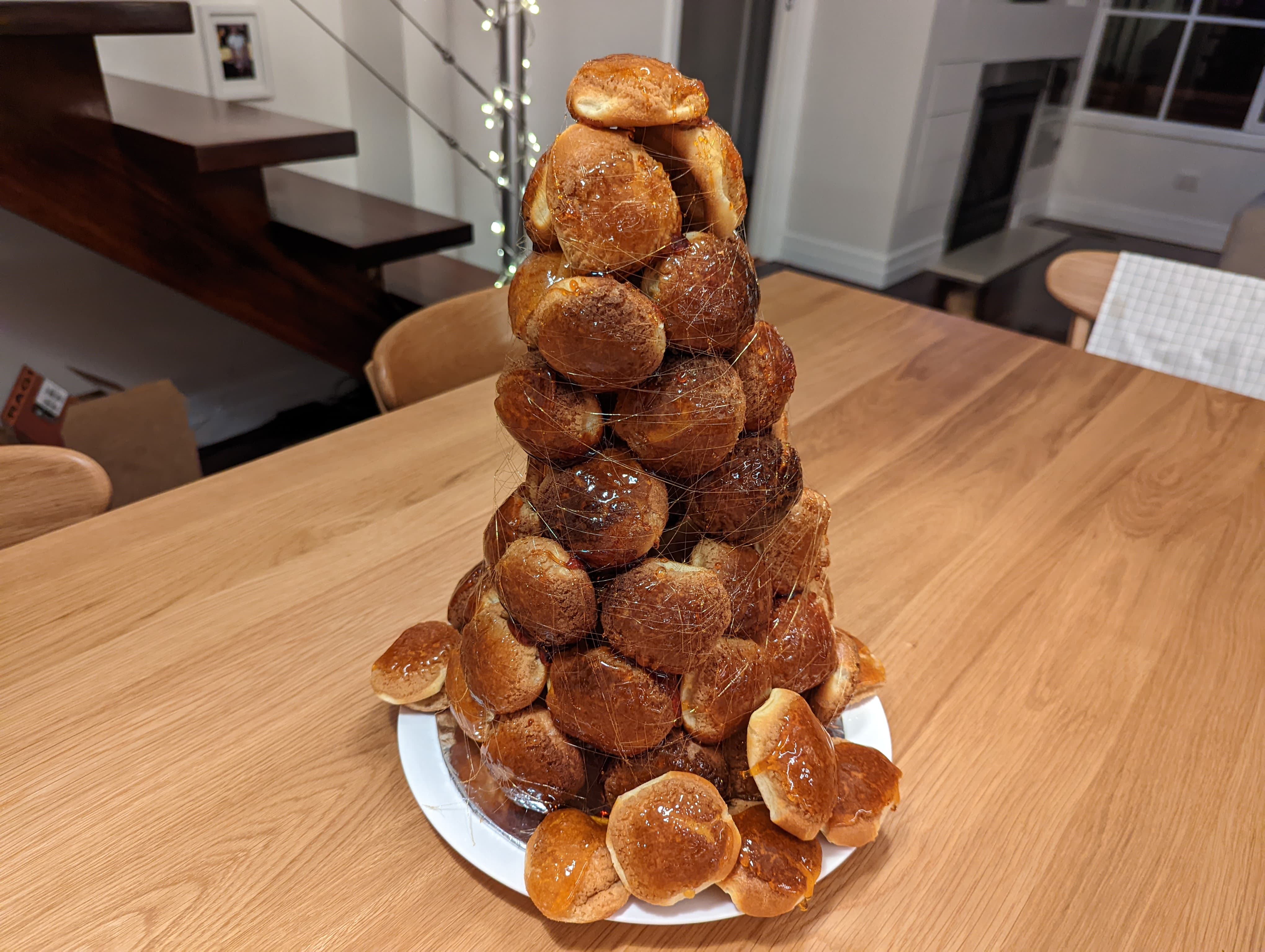 A tower of choux pastry on a plate, wrapped with spun sugar